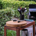 Bild in Galerie-Betrachter laden, Hackbrett aus Holz Natur, Rund Größe M, mit Griffeinkerbung, Milieubild im Garten, Zange liegt auf Brett
