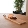 Bild in Galerie-Betrachter laden, Servierbrett oder Schneidebrett aus Eichenholz Natur mit Griff und schwarzem Lederband zum aufhängen, 800mm x 18mm x 25mm, Milieubild im Esszimmer auf Tisch, Brett mit Käse und Früchten drauf