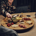 Bild in Galerie-Betrachter laden, Drehteller aus Eichenholz Natur, Größe XL, 75cm Durchmesser, rund, COOKX Logo eingraviert, Milieubild im Esszimmer, Teller mit verschiedenem Essen drauf steht auf Tisch