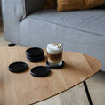 Bild in Galerie-Betrachter laden, Untersetzer aus schwarzer Eiche, 6 Stück, 10cm Durchmesser, die Untersetzer liegen auf einem Wohnzimmertisch, ein Kaffee steht auf einem der Untersetzer, Ansicht von der Seite