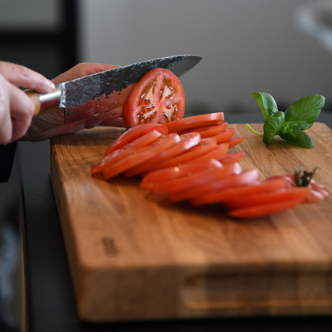 Hackbrett aus Eichenholz Natur, Größe M, COOKX Logo unten rechts eingraviert, Milieubild in Küche, Tomate wird auf Brett geschnitten