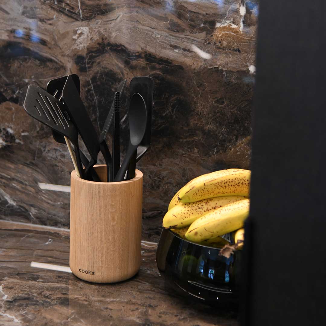 Küchenutensilienhalter aus Eichenholz Natur, Milieubild in Küche, im Halter sind schwarze Küchenutensilien, rechts daneben liegen Bananen in einer schwarzen Schüssel